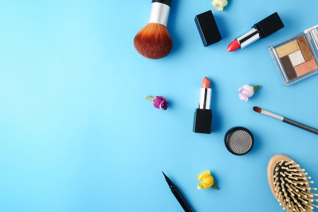 Vue de dessus des produits cosmétiques pour le maquillage sur un fond bleu.