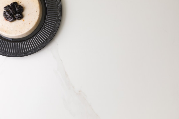 Vue de dessus d'un pudding de noix de coco aux prunes dans une plaque noire dans une table en marbre et un espace pour le texte