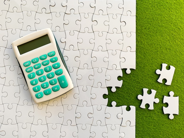 Vue de dessus, puzzle blanc et calculatrice sur vert