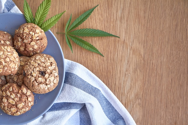 Vue de dessus de quelques biscuits de pot d'avoine sur une plaque grise sur une serviette rayée sur une surface en bois claire.