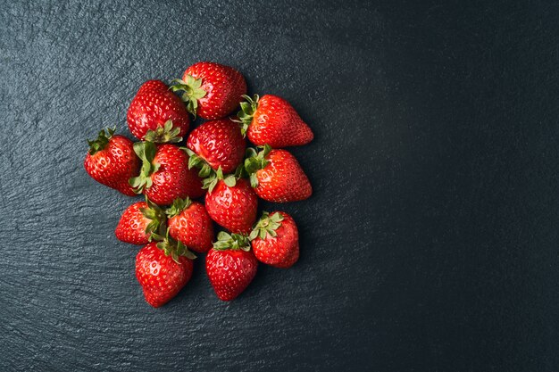 Vue de dessus de quelques fraises rouges sur dark