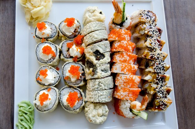Vue de dessus des rouleaux de sushi au saumon, anguille, concombre, fromage et wasabi sur l'assiette au restaurant.