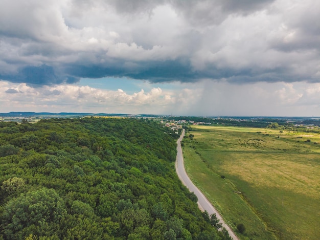 Vue de dessus de la route près de la forêt d'un côté et des champs de l'autre par temps couvert