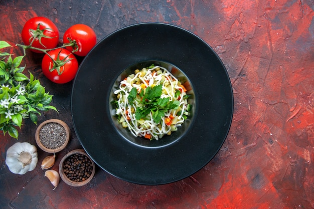 vue de dessus salade de légumes décorée à l'intérieur de la plaque avec des tomates rouges et des assaisonnements surface sombre repas santé régime alimentaire déjeuner couleur horizontale cuisine