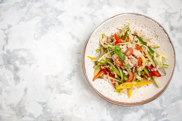 Vue de dessus de la salade de poulet aux légumes sur le côté gauche sur une surface blanche tachée