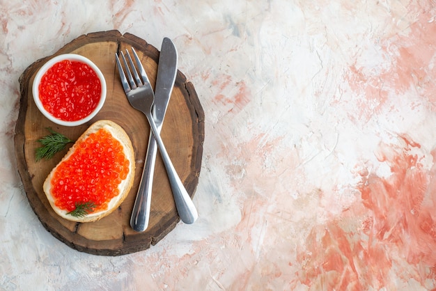 vue de dessus sandwich au caviar avec couverts sur une planche à découper sur une surface claire