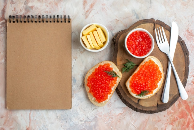 vue de dessus des sandwichs au caviar avec des couverts et du fromage sur une planche à découper sur une surface claire