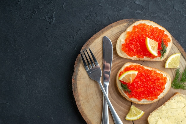 vue de dessus des sandwichs au caviar avec des couverts sur une surface sombre de la planche à découper