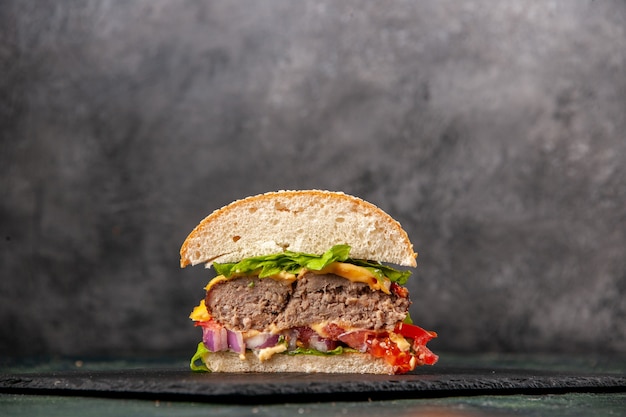 Vue de dessus des sandwichs savoureux coupés sur un plateau noir sur une surface de couleur mélange sombre