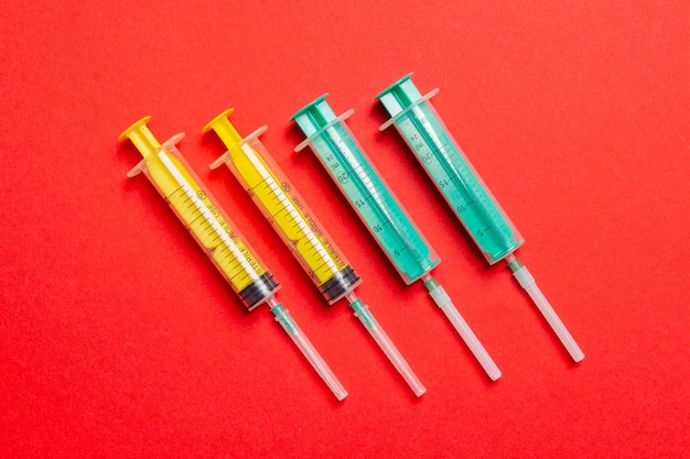 Vue de dessus des seringues médicales avec des aiguilles sur fond rouge avec espace de copie. Concept de traitement par injection.