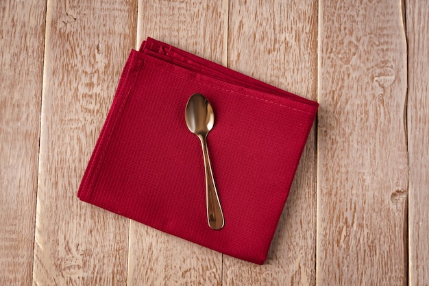 Vue de dessus de la serviette en tissu de couleur rouge et servi de cuillère à thé sur la table en bois.