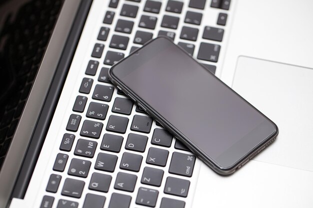 Vue de dessus d'un seul smartphone avec écran noir vierge pour votre conception sur ordinateur portable