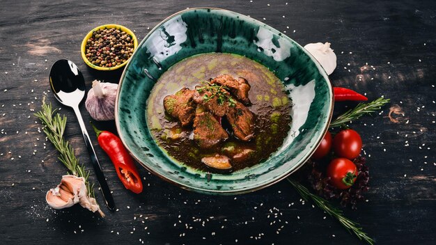 Vue de dessus de la soupe au boeuf et aux légumes Sur un fond en bois noir Espace de copie