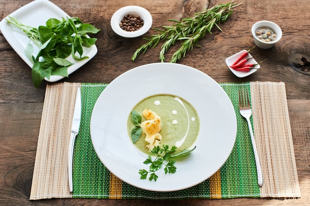 Vue de dessus de la soupe aux courgettes dans une assiette blanche sur une table en bois