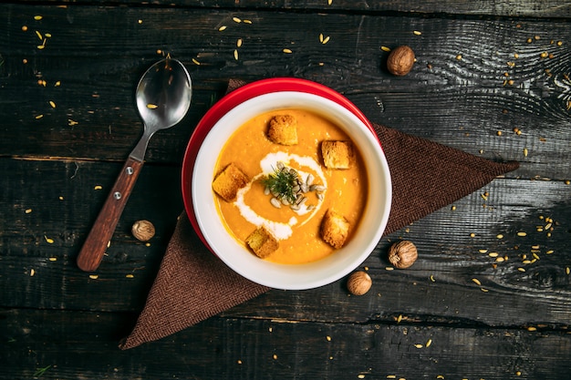 Vue de dessus sur la soupe de purée de citrouille saine et appétissante sur la serviette sur la table en bois