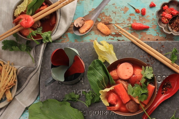 Photo vue de dessus soupe thaïlandaise épicée tom yum aux fruits de mer, servie sur un bol brun rustique, sur fond de bois vert