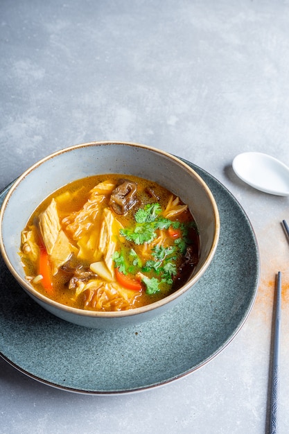 Vue de dessus soupe végétalienne avec tomates, nouilles, champignons shiitake, persil et tofu grillé