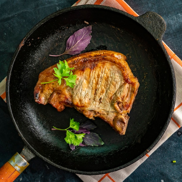 Vue de dessus d'un steak de bœuf frit au porc dans un stylo en fonte avec des herbes et des épices