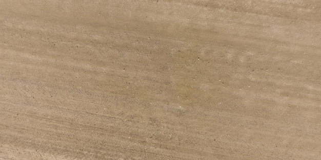 Vue de dessus de la surface de la route de gravier faite de petites pierres et de sable avec des traces de pneus de voiture