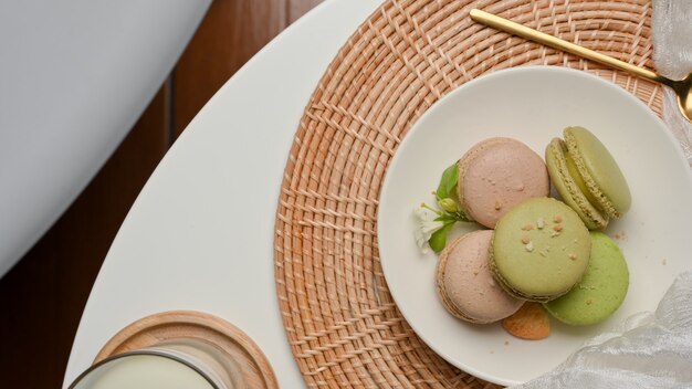 Vue de dessus de la table basse avec une assiette de macarons colorés français et un verre de lait