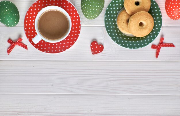 Vue de dessus sur une table en bois clair avec une tasse de café, des biscuits et des oeufs de Pâques