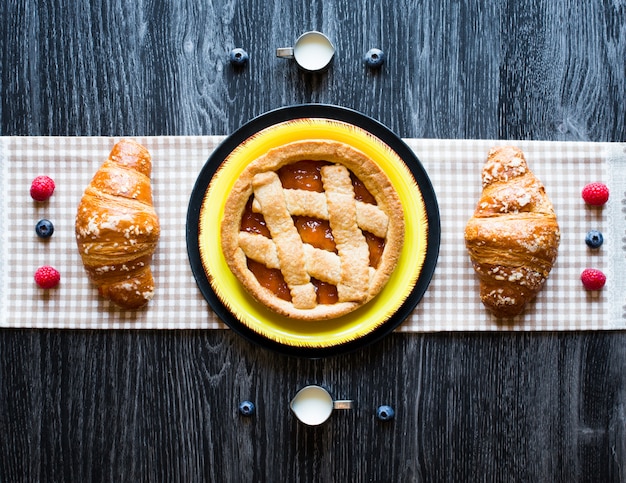 Vue de dessus d'une table en bois pleine de gâteaux, fruits, café, biscuits, épices et plus