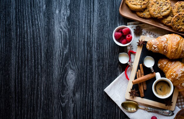 Vue de dessus d'une table en bois pleine de gâteaux, fruits, café, biscuits, épices et plus