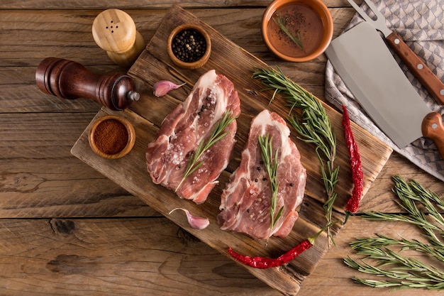 Vue de dessus d'une table en bois avec des steaks de porc grillés à partir d'épices à viande de fermier pour la cuisson sur une planche de bois