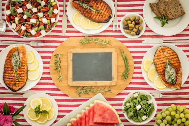 Vue de dessus de la table avec du poisson, des salades, des fruits et légumes