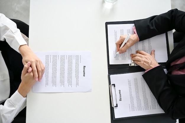 Vue de dessus d'une table avec une femme responsable des ressources humaines et un candidat lors d'un entretien d'embauche