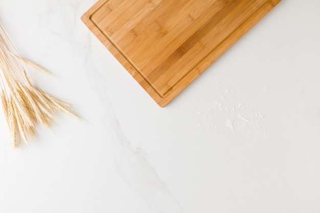 Vue de dessus d'une table en marbre avec une planche de bois, du blé et de la farine avec un espace pour le texte