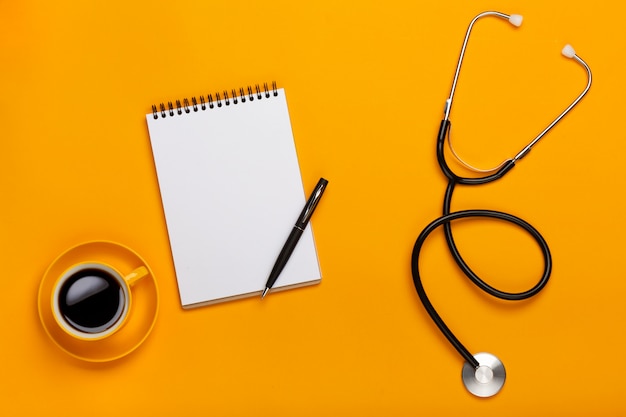 Vue De Dessus D'une Table De Médecin Avec Un Bloc-notes Et Un Stylo Stéthoscope, Un Clavier, Une Ordonnance Et Des Pilules, Une Tasse De Café Sur Un Fond Jaune