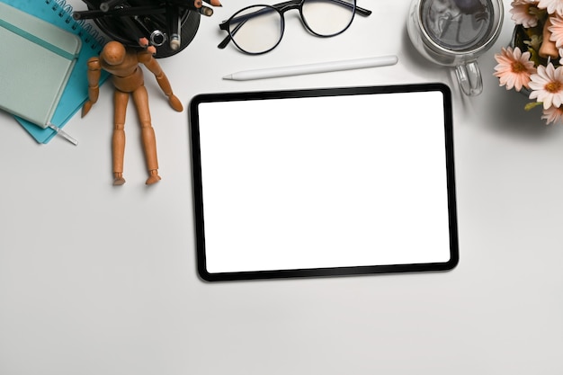 Vue de dessus, tablette numérique avec écran blanc sur un bureau blanc.