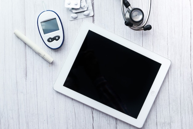 Vue de dessus de la tablette numérique, des pilules et de l'outil de mesure du diabète sur la table