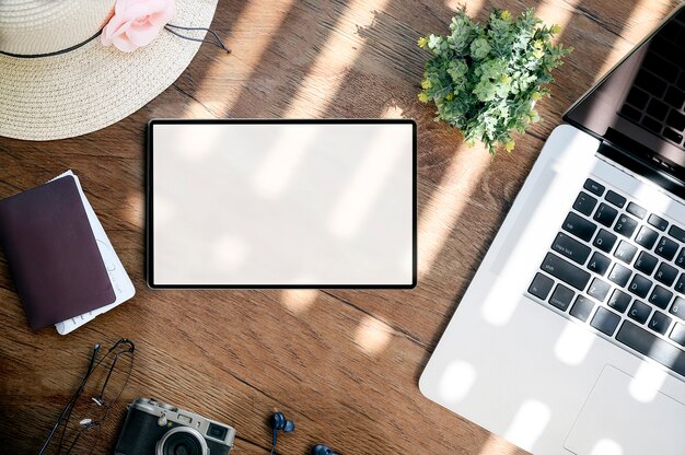 Vue de dessus de tablette, ordinateur portable, passeport, chapeau, appareil photo, lunettes et smartphone sur une table en bois, concept de voyage.