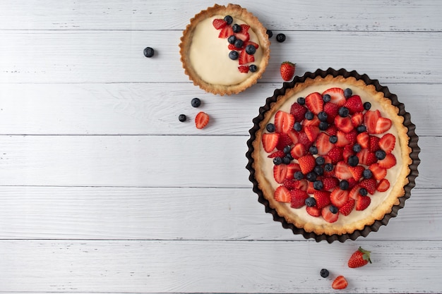 Vue de dessus tarte fraise myrtille crème blanc table en bois