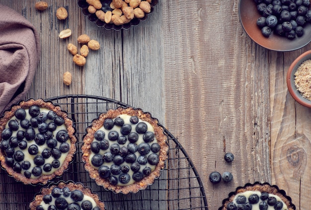 Vue De Dessus Sur Les Tartes Aux Myrtilles Entières Avec Crème à La Vanille Sur Bois Rustique