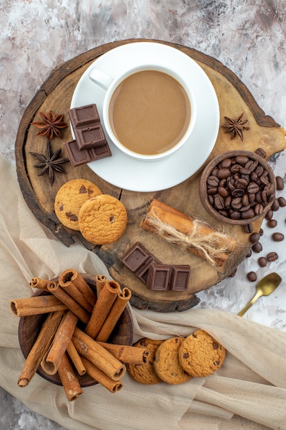 vue de dessus tasse de biscuits au café bol avec des grains de café chocolat bâtons de cannelle dans un bol anis sur planche de bois sur table