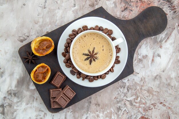 vue de dessus tasse de café avec biscuits au chocolat anis grains de café sur soucoupe sur planche de bois sur table