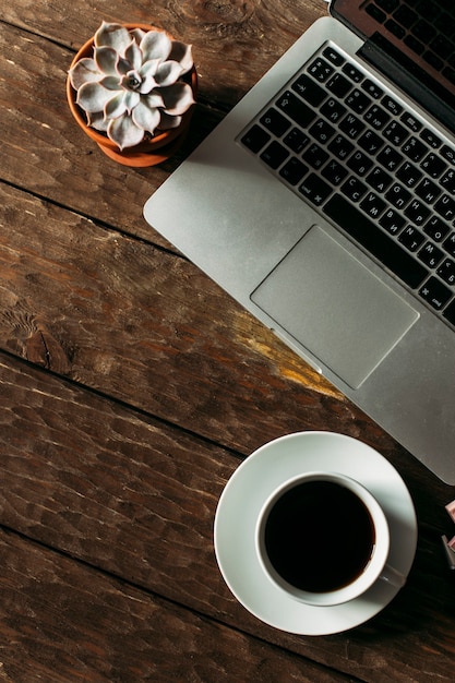 vue de dessus d'une tasse de café blanche et d'un ordinateur portable sur une table en bois