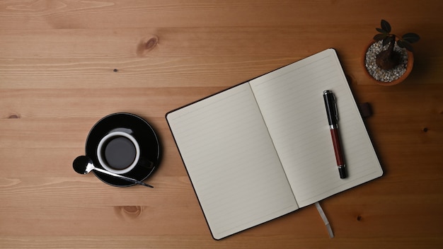 Vue de dessus tasse de café, cactus et cahier sur un bureau en bois.