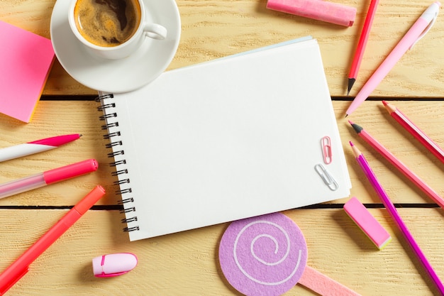 Vue de dessus, tasse à café avec café, stylo portant un cahier vierge,