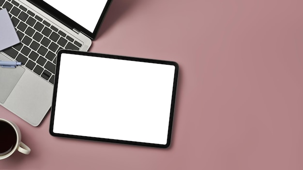 Vue de dessus de la tasse à café et du bloc-notes pour ordinateur portable tablette numérique sur fond rose Espace de copie pour les informations textuelles ou le contenu