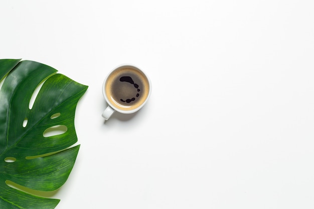 Vue de dessus de la tasse de café et de la feuille de monstera