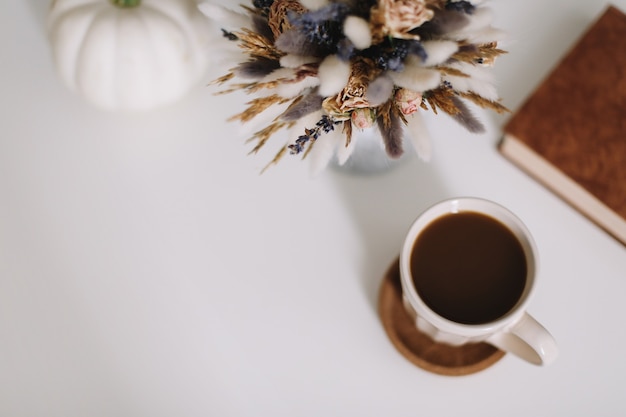 Vue de dessus d'une tasse de café et de fleurs séchées sur fond blanc Mise à plat