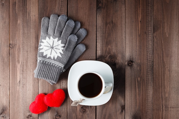 Vue de dessus de la tasse de café noir avec des gants sur fond de bois