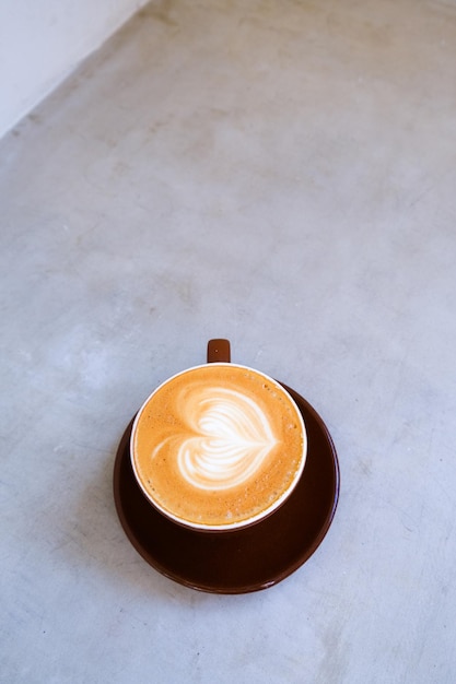 Vue de dessus d'une tasse de cappuccino avec un bel art latte sur fond de béton