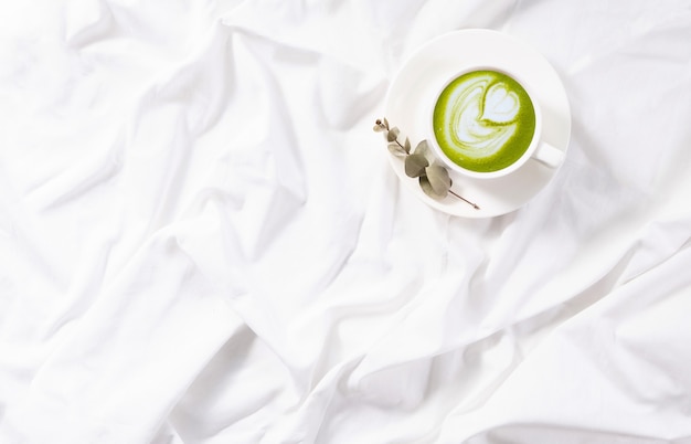 Vue de dessus tasse de matcha latte au lit. Flatlay confortable. Routine matinale. Copiez l'espace. Concept minimalisme