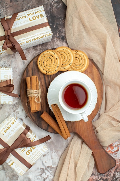 Vue de dessus tasse de thé avec des biscuits sucrés et des cadeaux sur fond clair cérémonie de pause biscuit couleur tarte au café au sucre