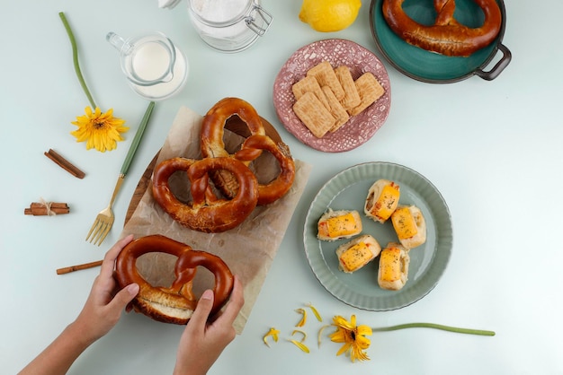 Vue de dessus Temps de collation à plat avec main, bretzel, biscuit et rouleau de pâtisserie avec du fromage fondu. Convient pour les flux de médias sociaux ou la publicité